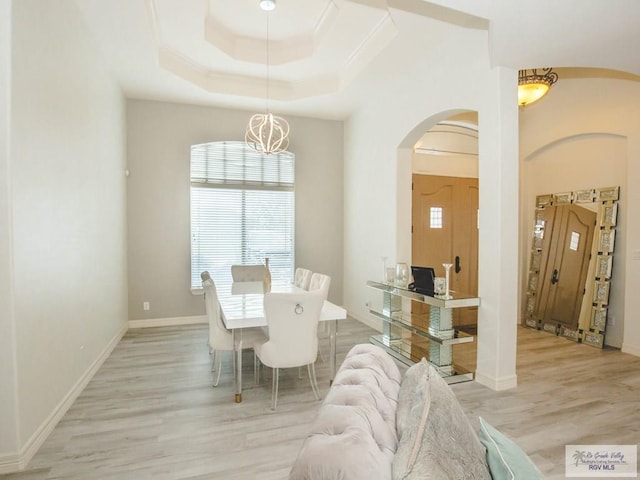 100 Paloma St, San Benito, TX 78586 - dining area featuring ornamental molding, arched walkways, light wood finished floors, a raised ceiling, and a chandelier
