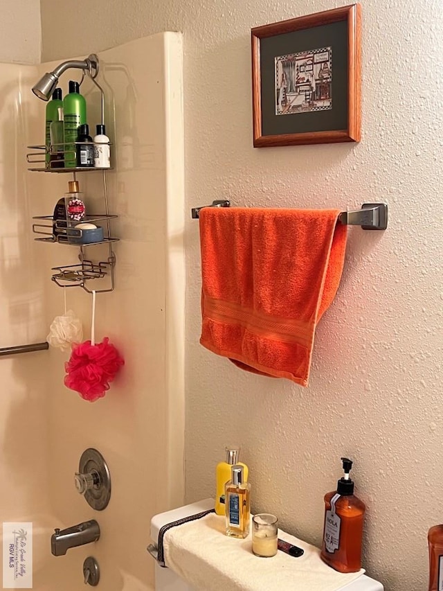 bathroom with shower / bathing tub combination and a textured wall