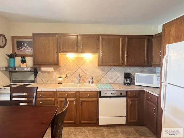 kitchen with decorative backsplash, a sink, tile countertops, and white appliances