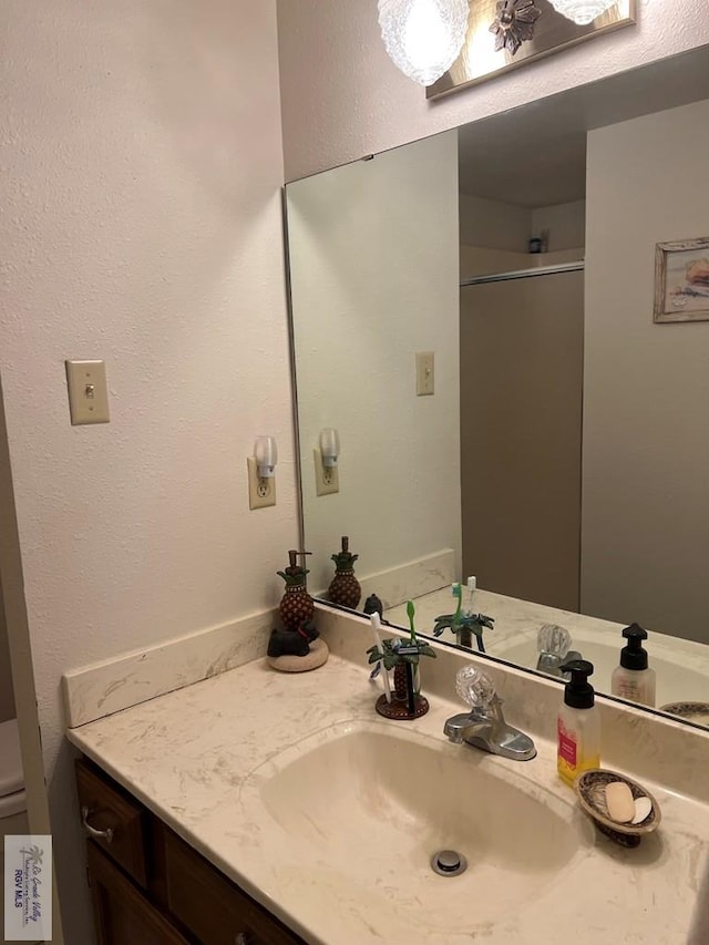 bathroom with toilet, vanity, and a shower with shower door