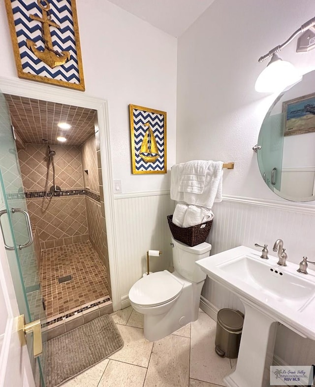 107 E Palm St Unit B, South Padre Island, TX 78597 - full bath featuring a sink, a shower stall, toilet, a wainscoted wall, and tile patterned flooring