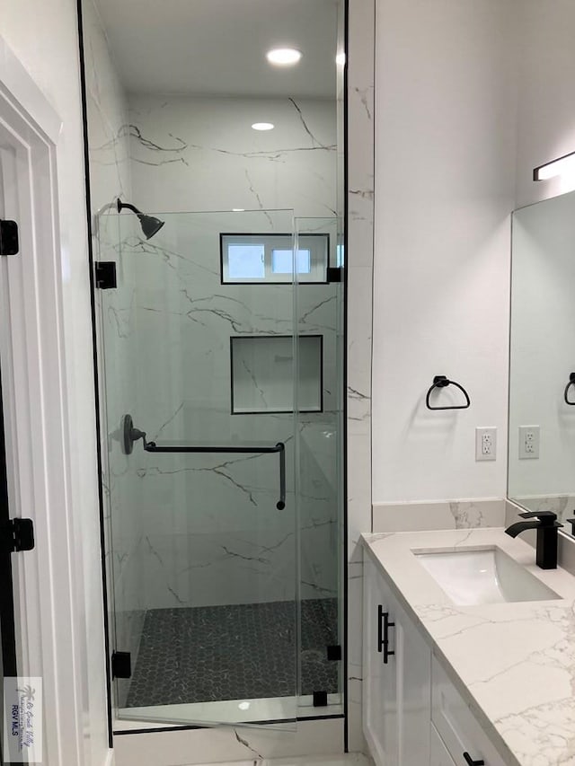 bathroom with a shower with door and vanity