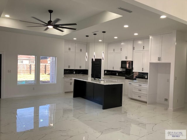 kitchen featuring a center island with sink, pendant lighting, white cabinets, and tasteful backsplash