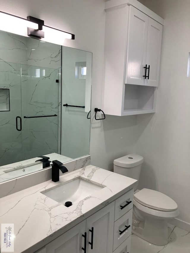 bathroom with vanity, toilet, and a shower with door