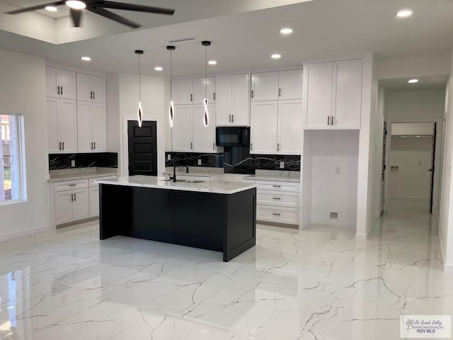 kitchen featuring white cabinets, a center island with sink, and hanging light fixtures