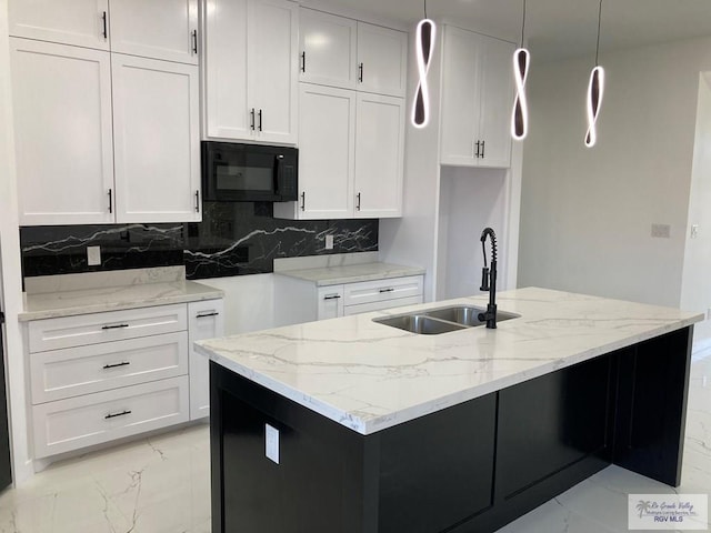 kitchen featuring tasteful backsplash, light stone counters, sink, white cabinetry, and hanging light fixtures