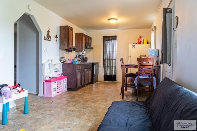 kitchen featuring dark brown cabinetry, white fridge, and black range with electric cooktop