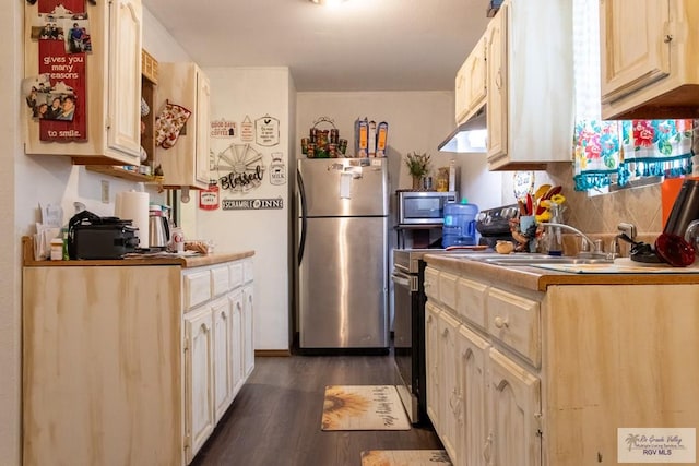 kitchen with light brown cabinetry, dark wood-type flooring, and appliances with stainless steel finishes