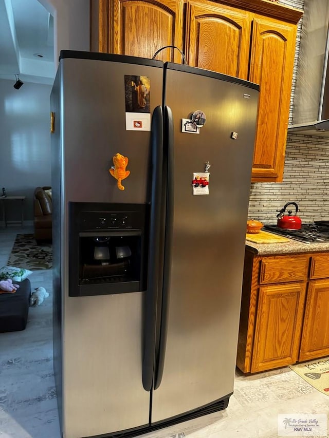 kitchen with tasteful backsplash, stainless steel fridge, and range hood