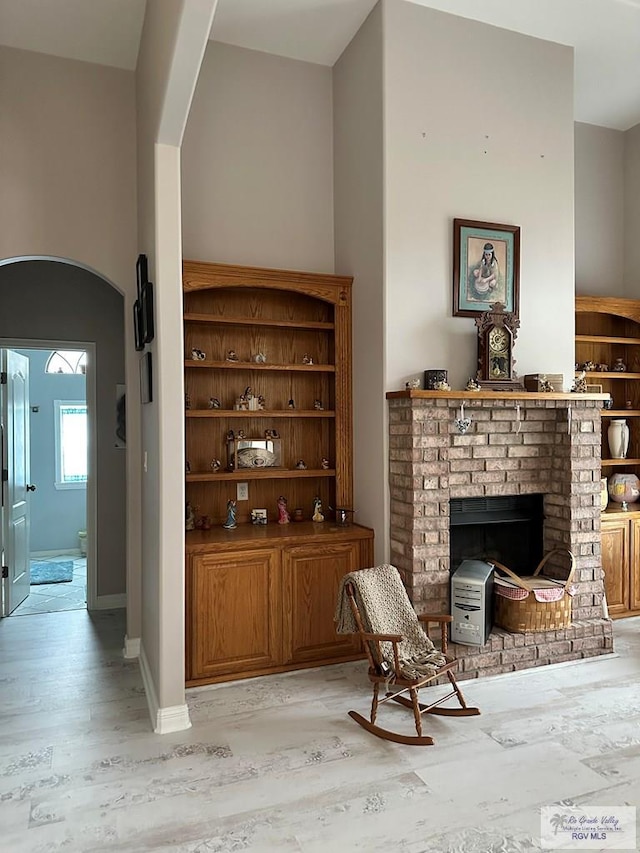 bar with a brick fireplace and light hardwood / wood-style flooring