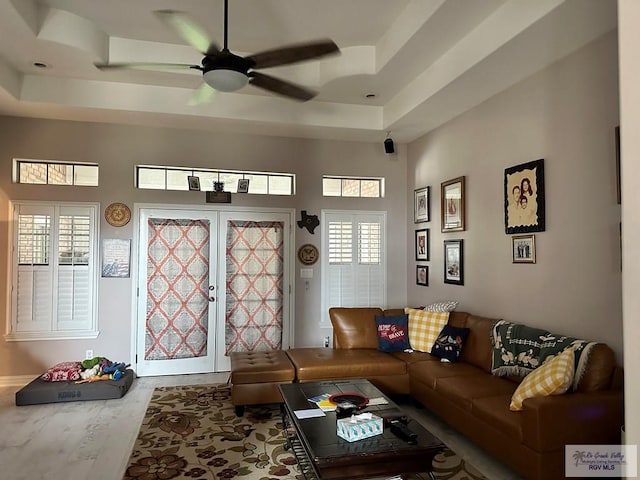 living room featuring a raised ceiling, ceiling fan, and a towering ceiling