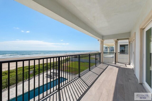 balcony with a water view and a view of the beach