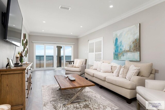 living room featuring a water view, light wood-type flooring, and ornamental molding