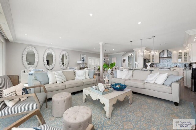 living room featuring decorative columns, a notable chandelier, and ornamental molding