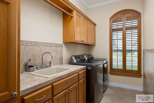 laundry area featuring cabinets, crown molding, sink, tile walls, and washing machine and clothes dryer