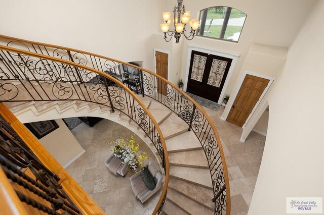 entryway featuring tile patterned flooring, a high ceiling, french doors, and a notable chandelier