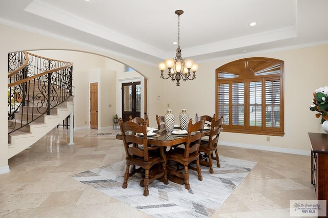 dining room with a raised ceiling, crown molding, and a notable chandelier