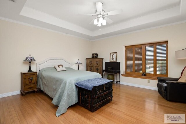 bedroom featuring a raised ceiling, ceiling fan, hardwood / wood-style floors, and crown molding