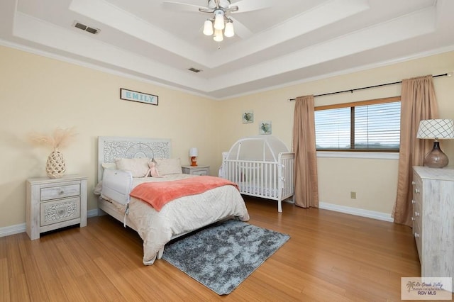 bedroom featuring a tray ceiling, ceiling fan, and hardwood / wood-style floors