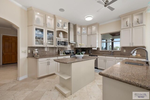 kitchen featuring stainless steel appliances, a kitchen island, wall chimney exhaust hood, and sink