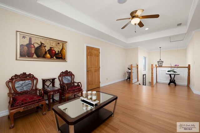 living room featuring ceiling fan, ornamental molding, and light wood-type flooring