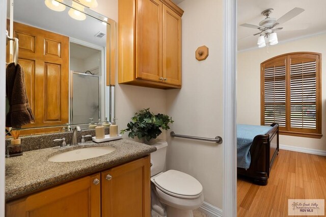 bathroom with vanity, hardwood / wood-style flooring, ceiling fan, toilet, and an enclosed shower