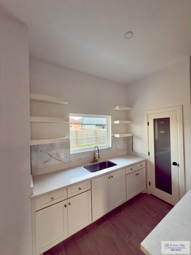kitchen with wood finish floors, light countertops, open shelves, and a sink