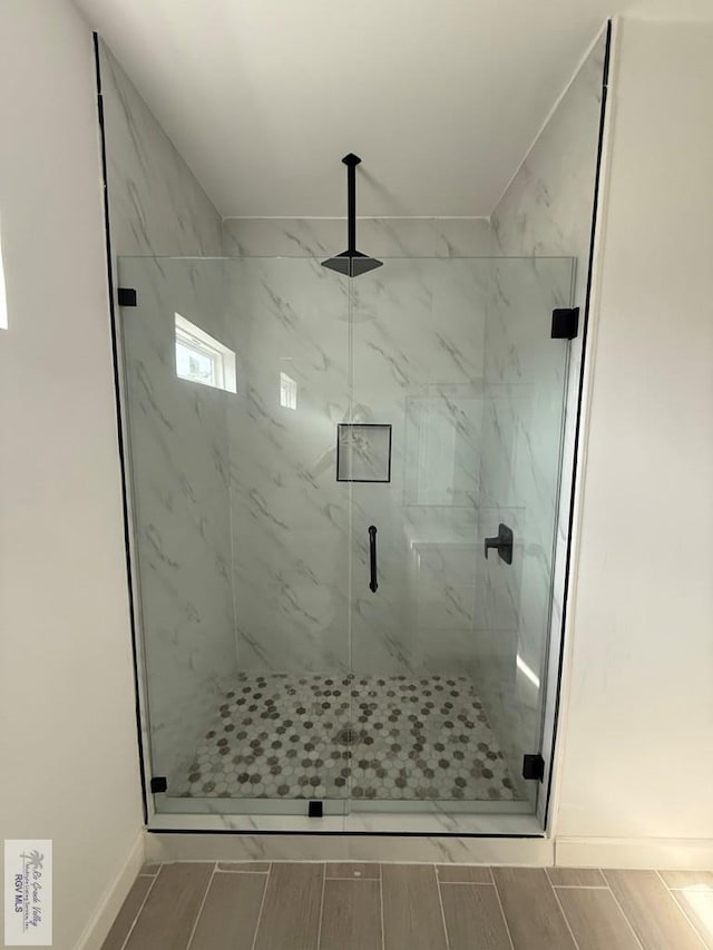 bathroom with wood tiled floor, a marble finish shower, and baseboards