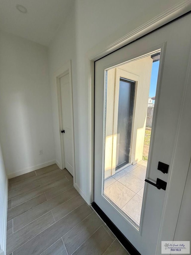 doorway with baseboards and wood finished floors