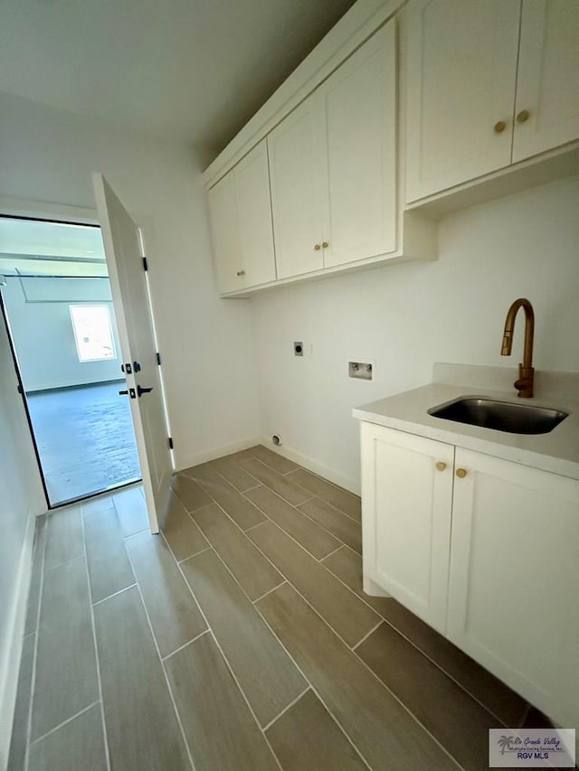 clothes washing area featuring a sink, cabinet space, electric dryer hookup, washer hookup, and baseboards