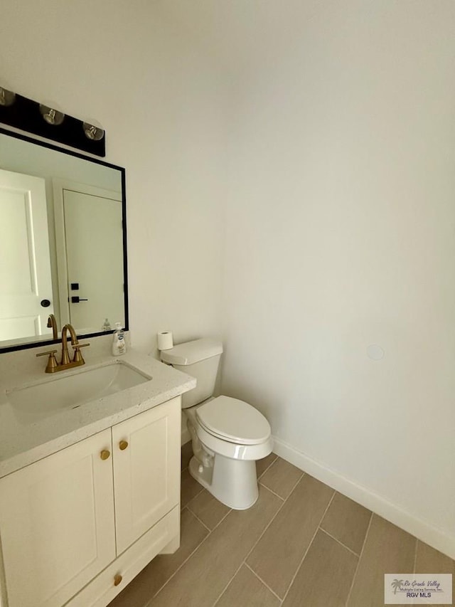 bathroom featuring toilet, baseboards, vanity, and wood finish floors