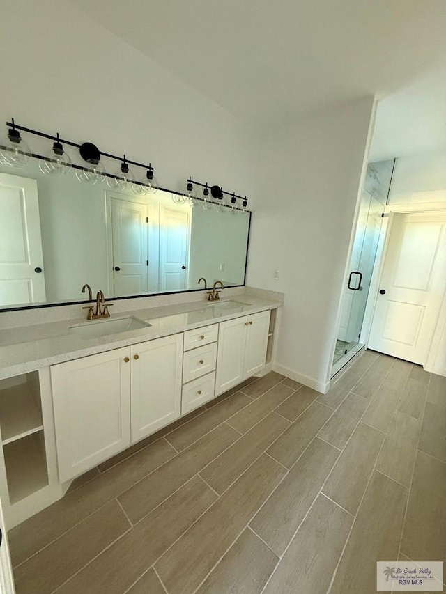 full bathroom featuring double vanity, a stall shower, wood finish floors, and a sink