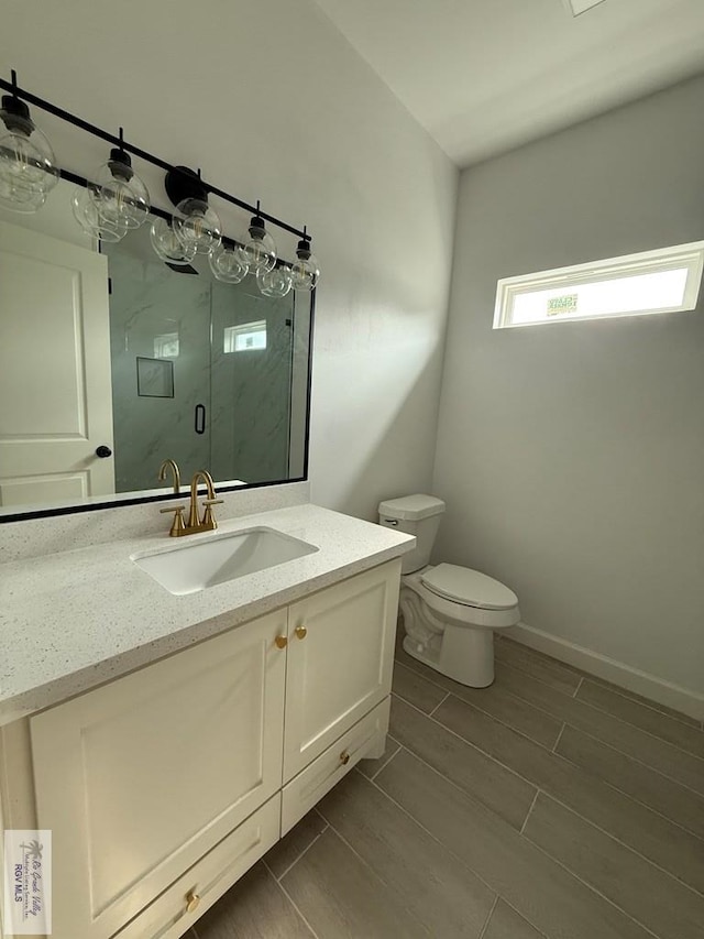 full bathroom with toilet, vanity, a stall shower, wood tiled floor, and baseboards