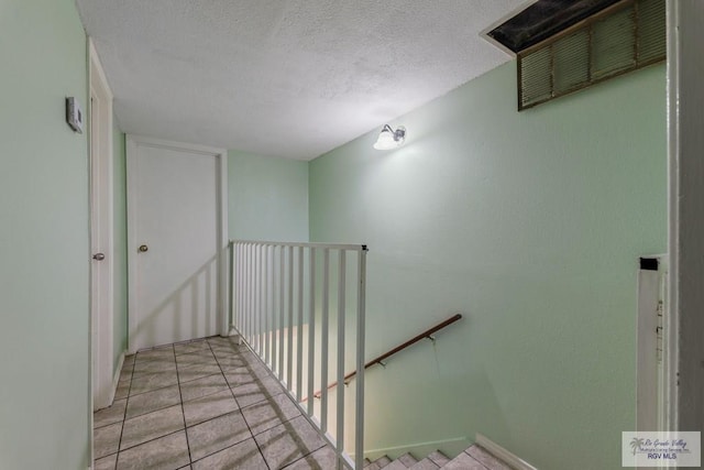 staircase with tile patterned flooring and a textured ceiling