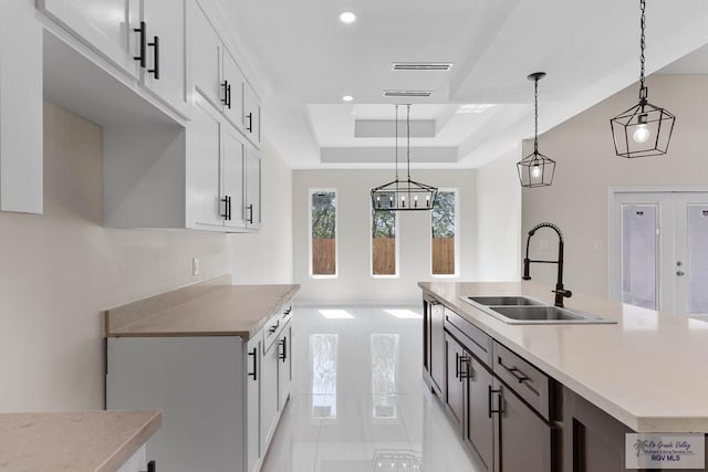 kitchen featuring light countertops, a tray ceiling, a sink, and white cabinetry