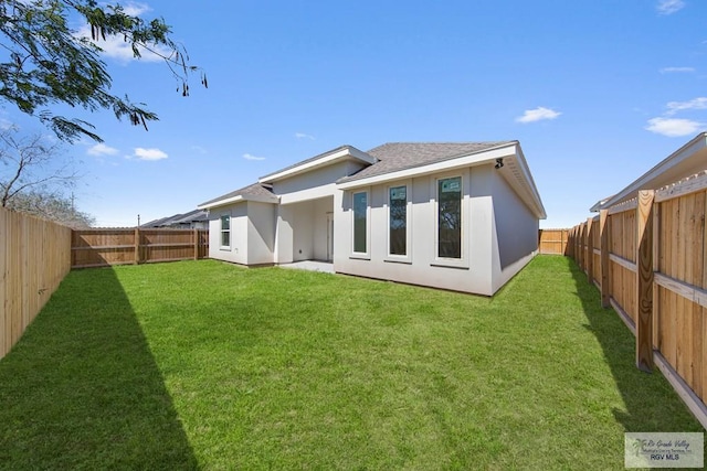 back of house featuring a shingled roof, a lawn, a fenced backyard, and stucco siding