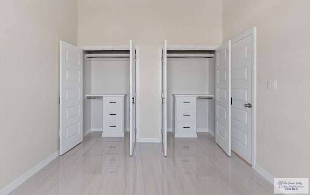 unfurnished bedroom with baseboards and two closets