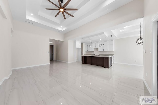 unfurnished living room featuring ceiling fan, baseboards, and a raised ceiling