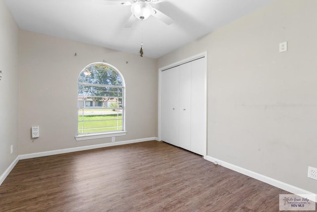 unfurnished bedroom featuring wood finished floors, a closet, baseboards, and ceiling fan