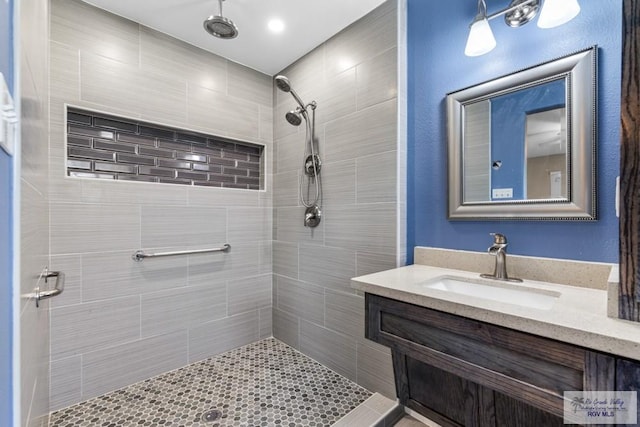 bathroom with a tile shower and vanity