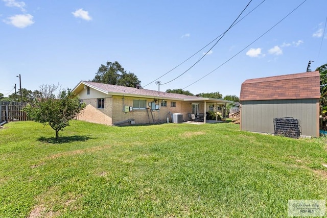 rear view of property featuring central AC, an outbuilding, brick siding, and a storage unit