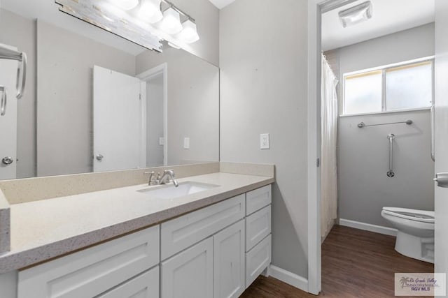 full bathroom with wood finished floors, toilet, vanity, and baseboards