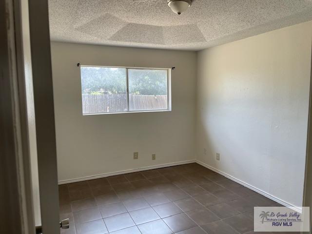 tiled spare room with a textured ceiling