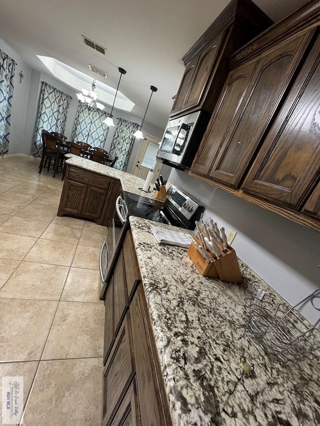 kitchen featuring dark brown cabinetry, a skylight, hanging light fixtures, a chandelier, and light tile patterned flooring