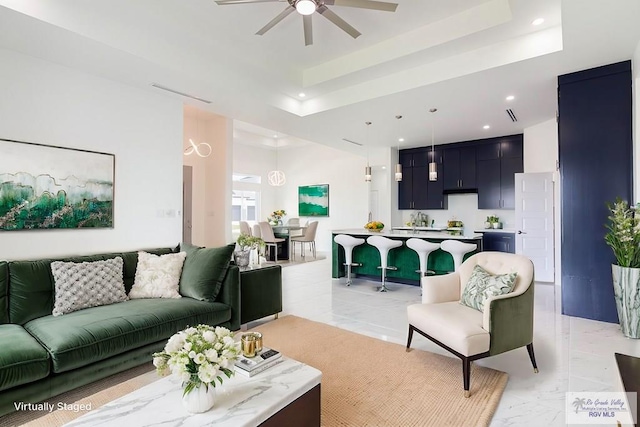 living room featuring a raised ceiling and ceiling fan