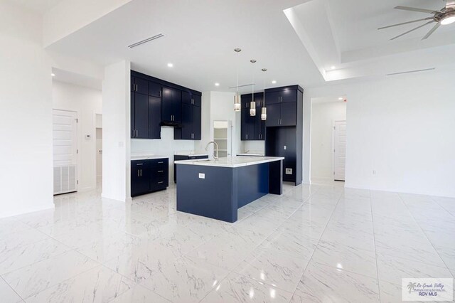 kitchen with sink, decorative light fixtures, ceiling fan, and an island with sink