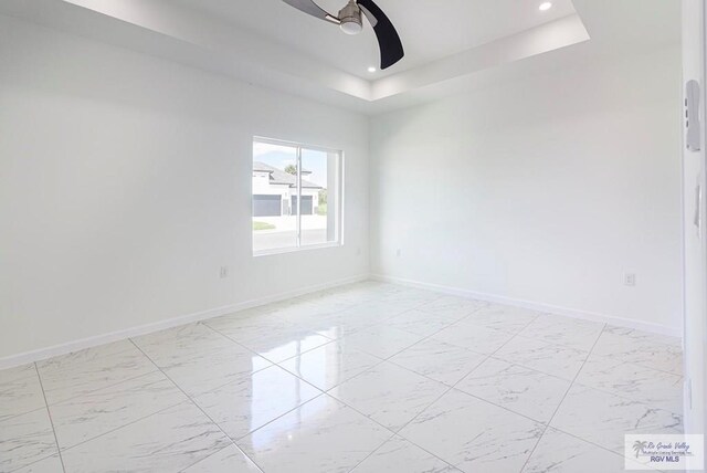 spare room featuring ceiling fan and a raised ceiling