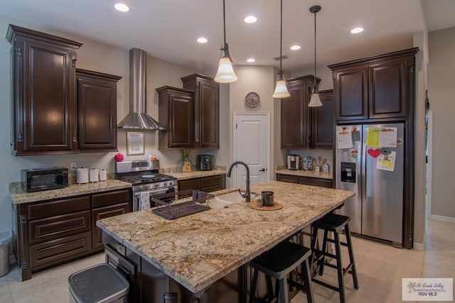 kitchen featuring a center island with sink, wall chimney exhaust hood, stainless steel appliances, and sink