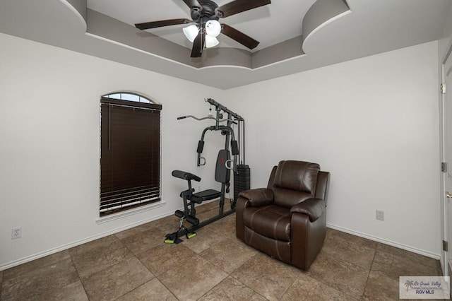 living area featuring a tray ceiling and ceiling fan