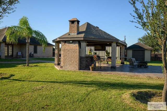 rear view of house featuring an outbuilding, a yard, and a patio area